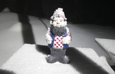 A garden gnome standing in a dusting of snow demonstrates how little snow there is.